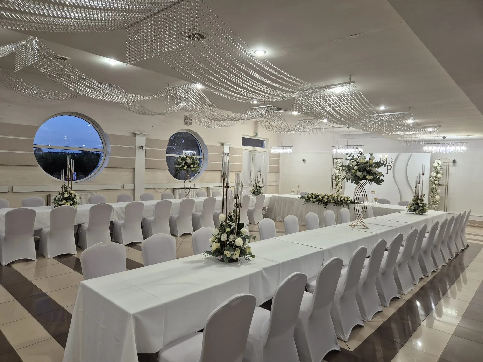 Sala weselna wieczorową porą z widokiem na okrągłe okna, Restauracja Szkiełka w Łowiczu