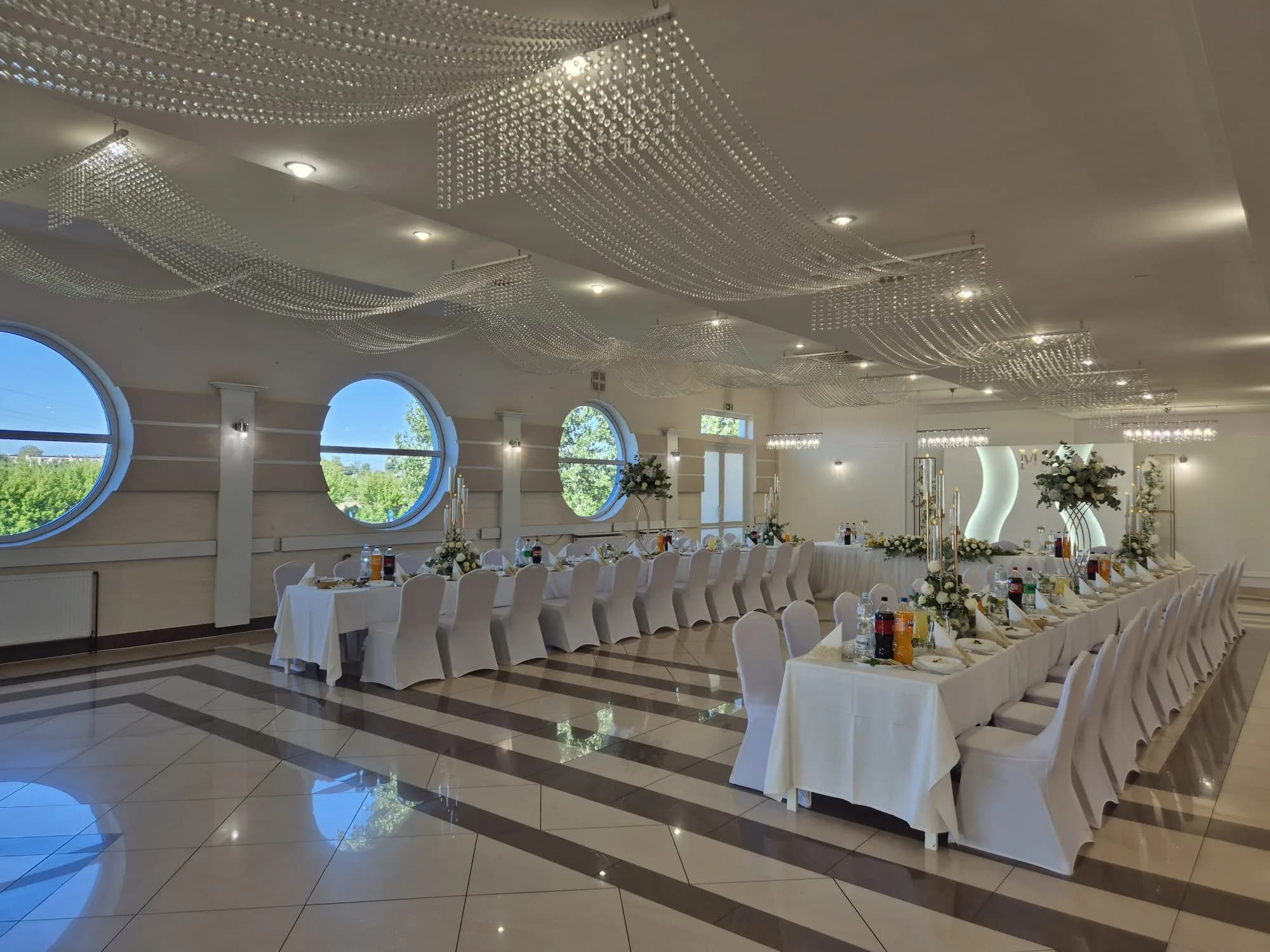 Sala weselna z okrągłymi oknami w słoneczny dzień, biały wystrój, Restauracja Szkiełka w Łowiczu