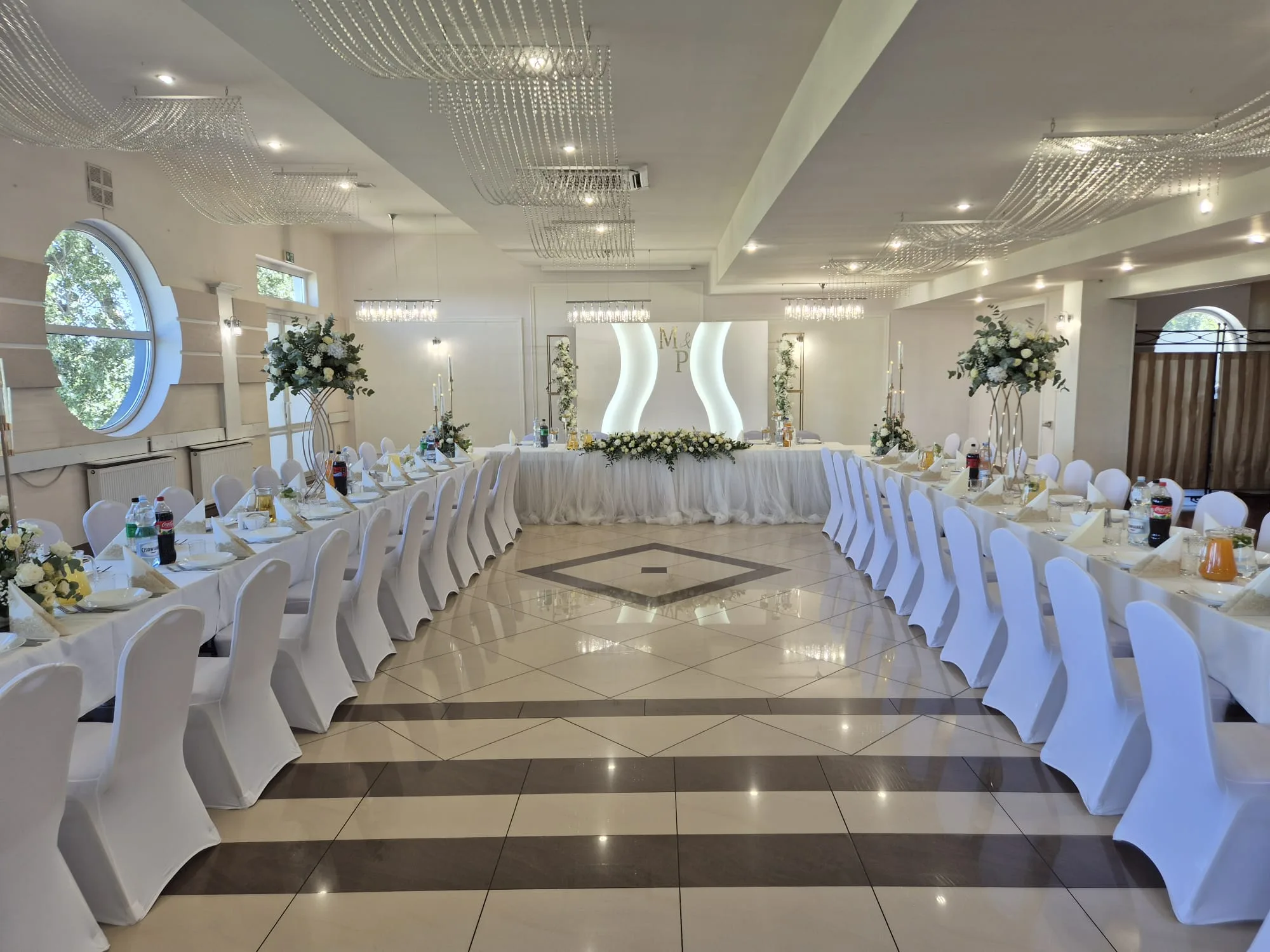 Pełna sala weselna z inicjałami pary młodej nad stołem prezydialnym, Restauracja Szkiełka